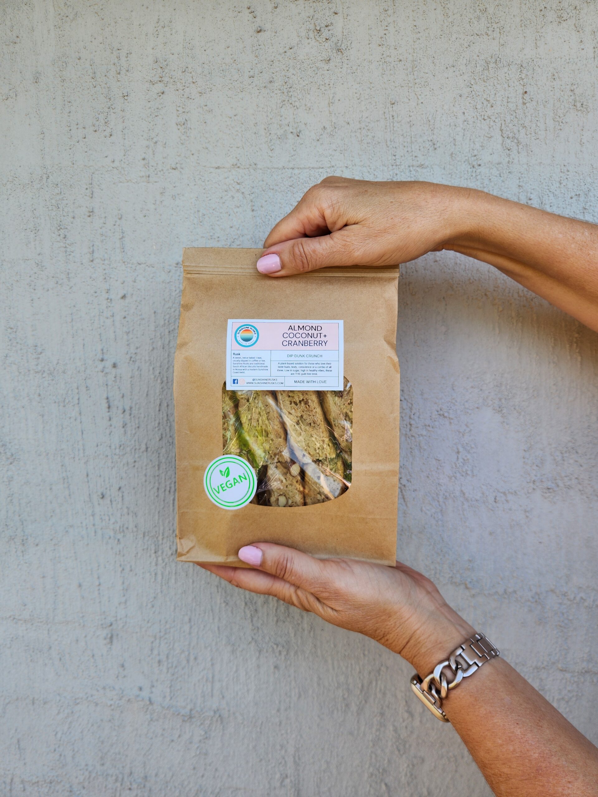 Hands holding a bag of Almond Coconut + Cranberry Rusks